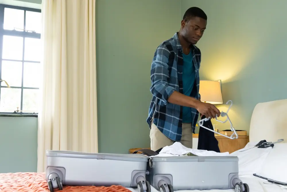 A black man packing for a two weeks vacation