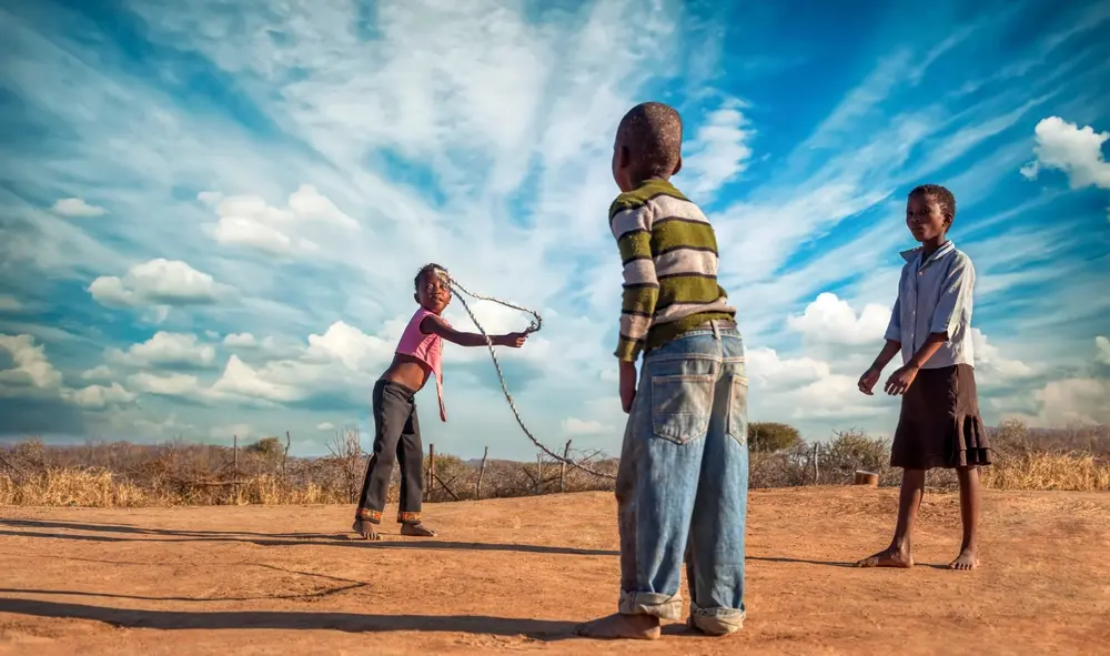 African kids, group of friends skipping rope in the yard, village in botswana