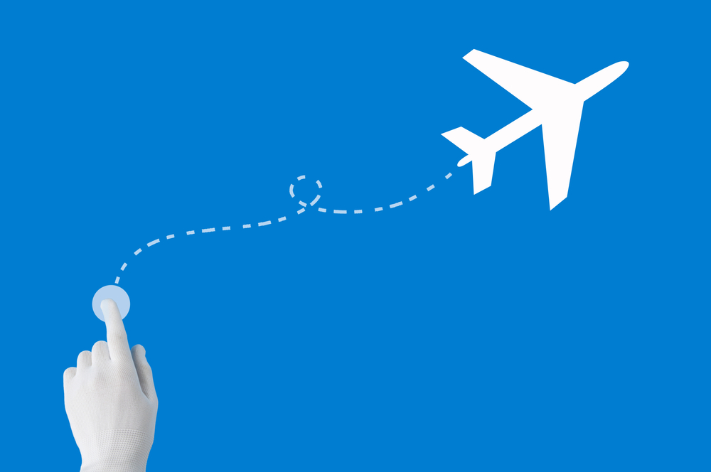 The index finger presses the button to search for the flight route on the plane and Cheap summer flights from Nigeria