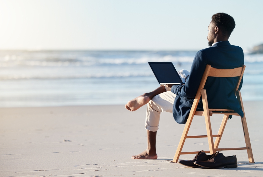 A black man that travelled with a digital nomad visa working at the beach