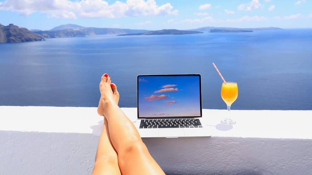 digital nomad visa lady with laptop and running remotely with bright scenic view of the Mediterranean Sea