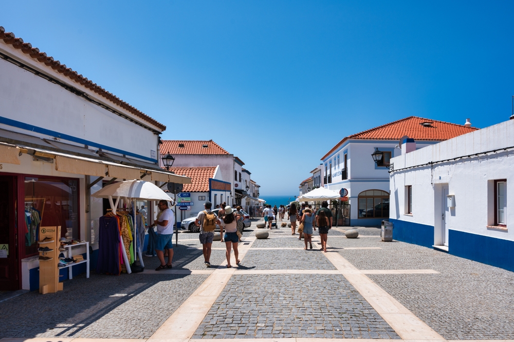 Alentejo Portugal. 04 august 2024. Porto Covo in alentejo Portugal, Charming cobblestone street in a Portuguese village with whitewashed houses, shops, and cafes. 